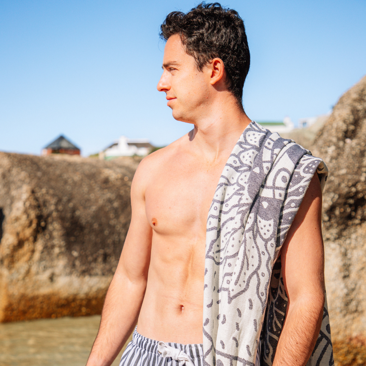Man with a patterned towel draped over his shoulder at the beach