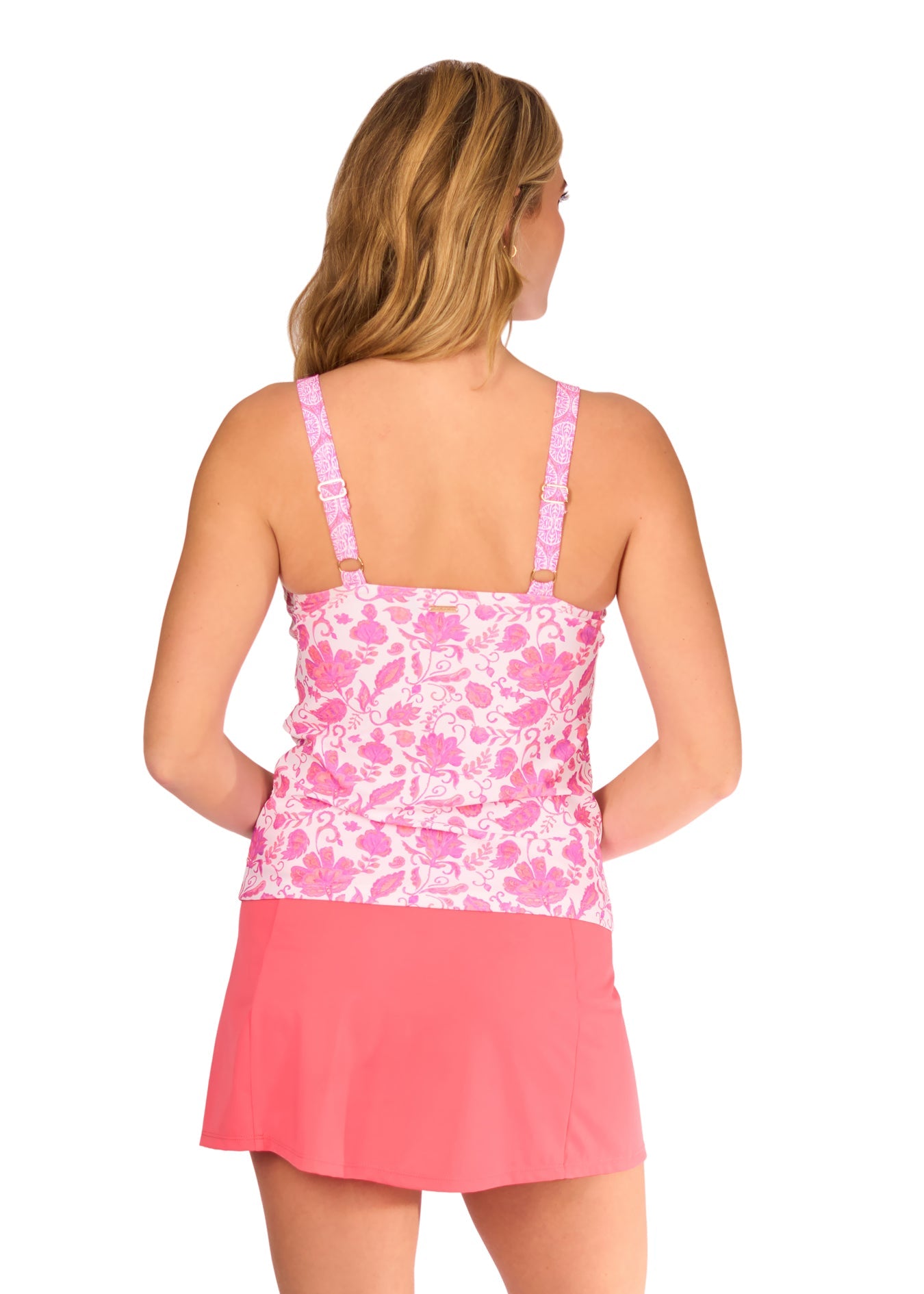 Woman wearing a pink floral tank top and pink skirt on a white background