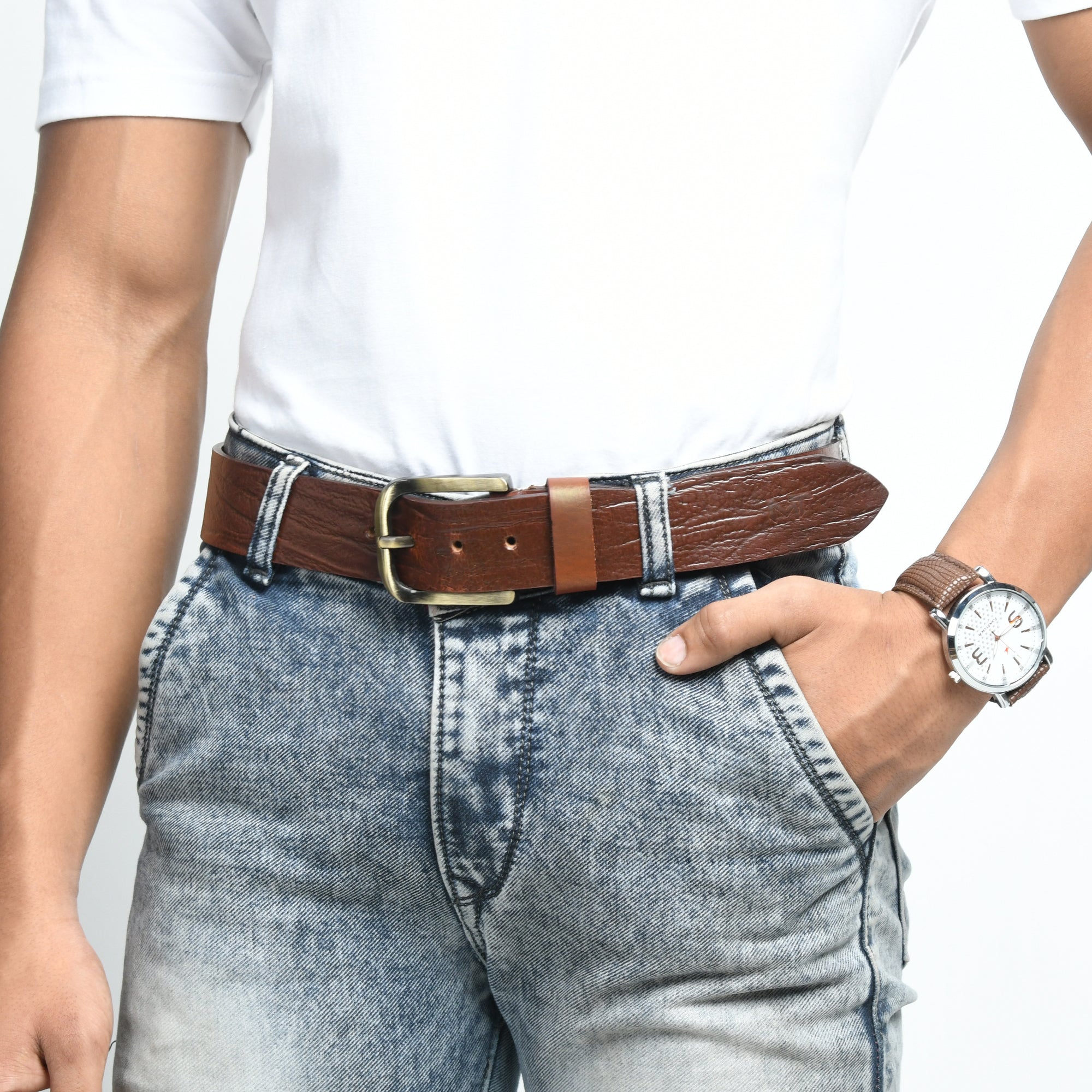 Person wearing a brown belt and watch with a white shirt and blue jeans on a light gray background