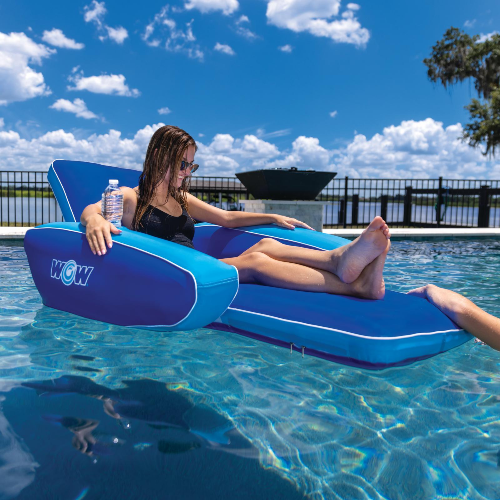 Person lounging on a blue inflatable pool float in a pool with a clear sky.