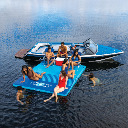 People enjoying a day out on a blue inflatable platform and boat on calm water.