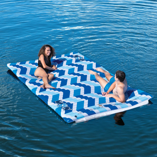 Two people on a blue and white inflatable pool mat in the water