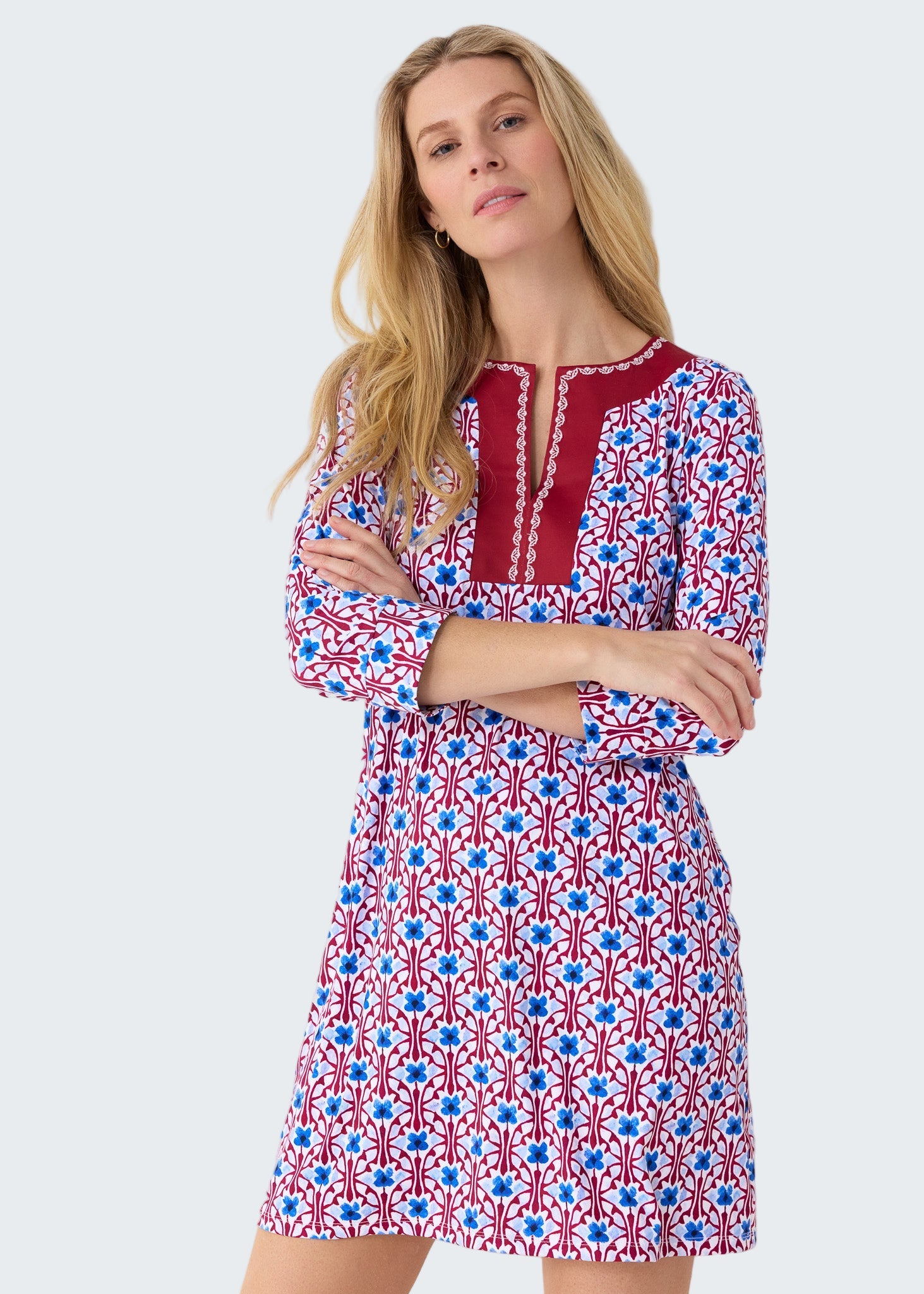 Woman wearing a patterned dress with red, white, and blue design on a plain background