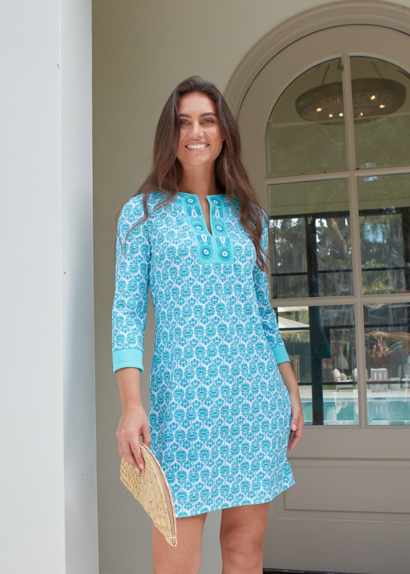 Woman wearing a blue patterned dress standing in front of a building entrance.