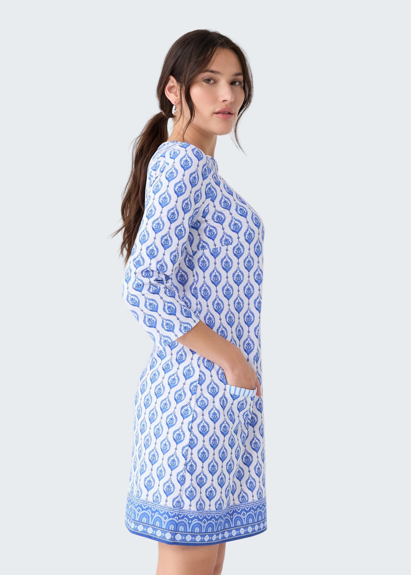 Woman wearing a blue and white patterned dress on a light gray background