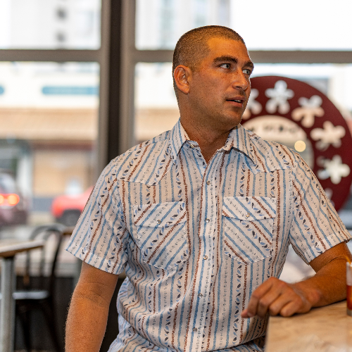 Man sitting at a table in a casual setting with a blurred background