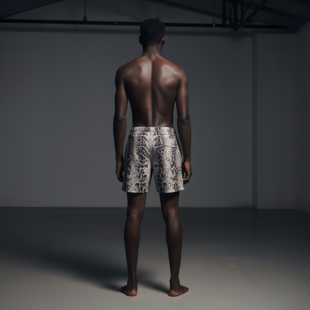 Man wearing patterned shorts standing against a dark background