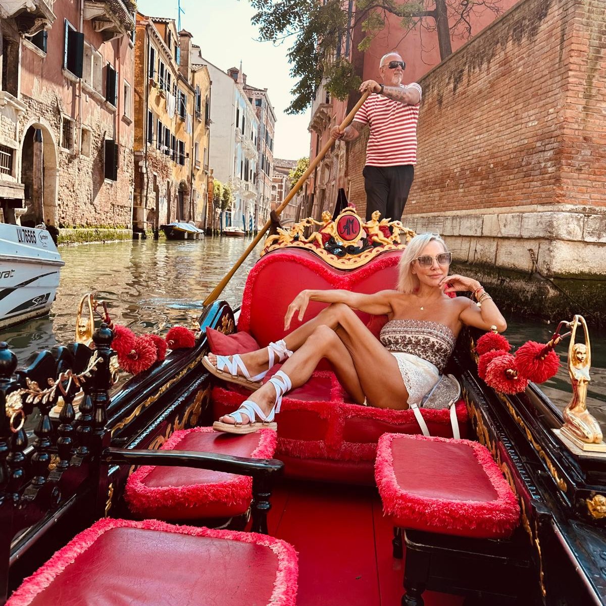 Woman in a gondola on a canal in Venice with a gondolier.