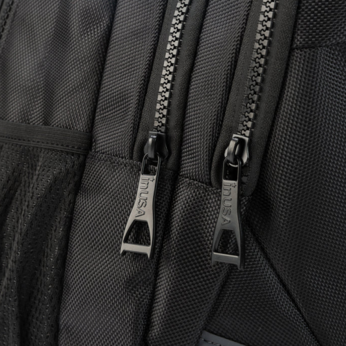 Close-up of a black backpack with zippers and 'TUSK' branding.