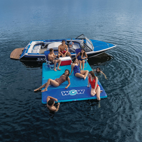 People enjoying a day on a floating platform with a small boat in the background on a lake.
