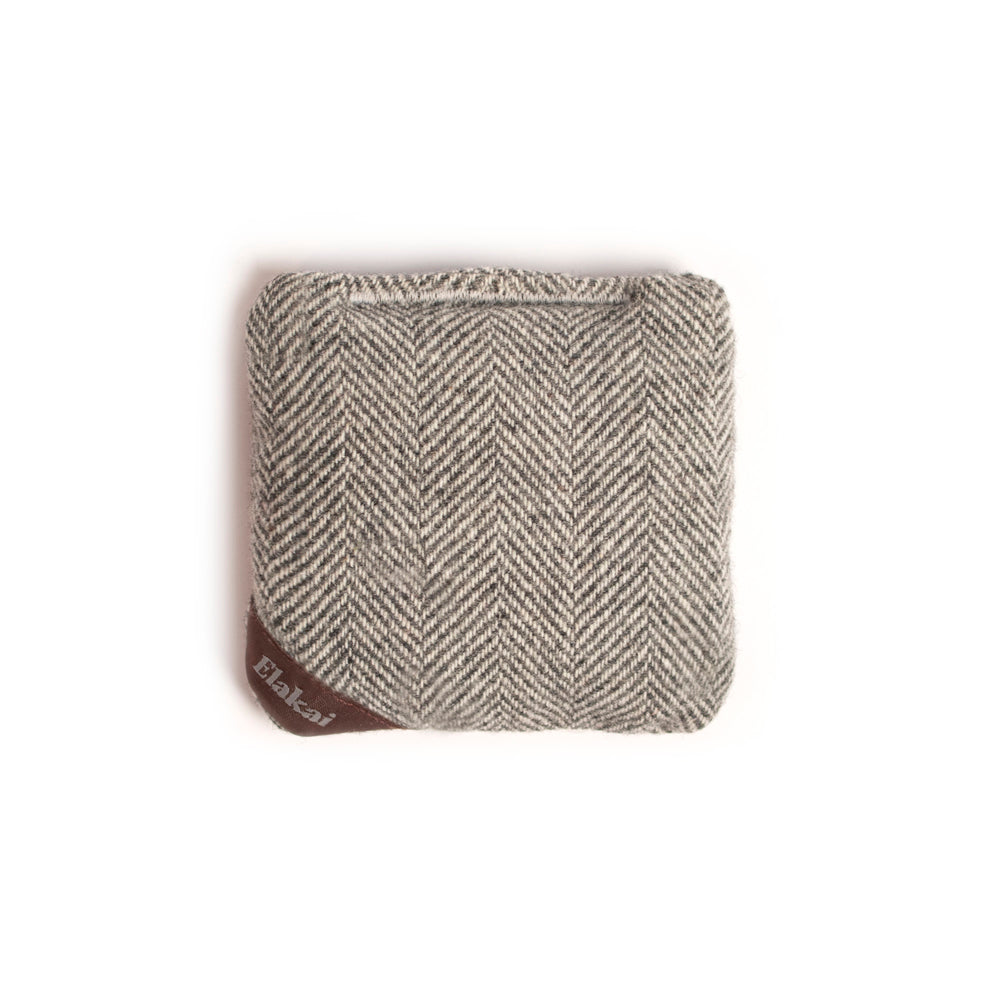 Herringbone patterned pouch with a brand label on a white background