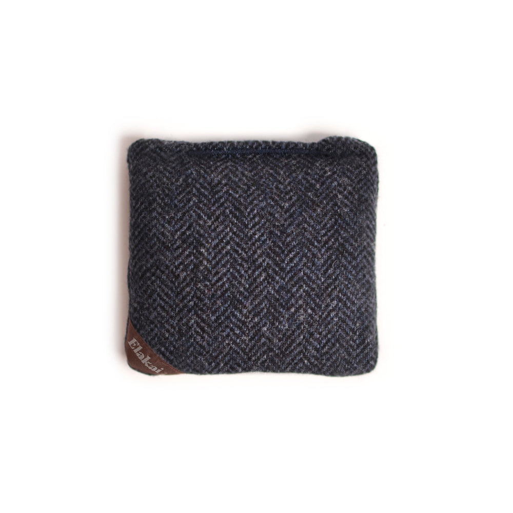 Dark gray herringbone patterned fabric square with a brand label on a white background