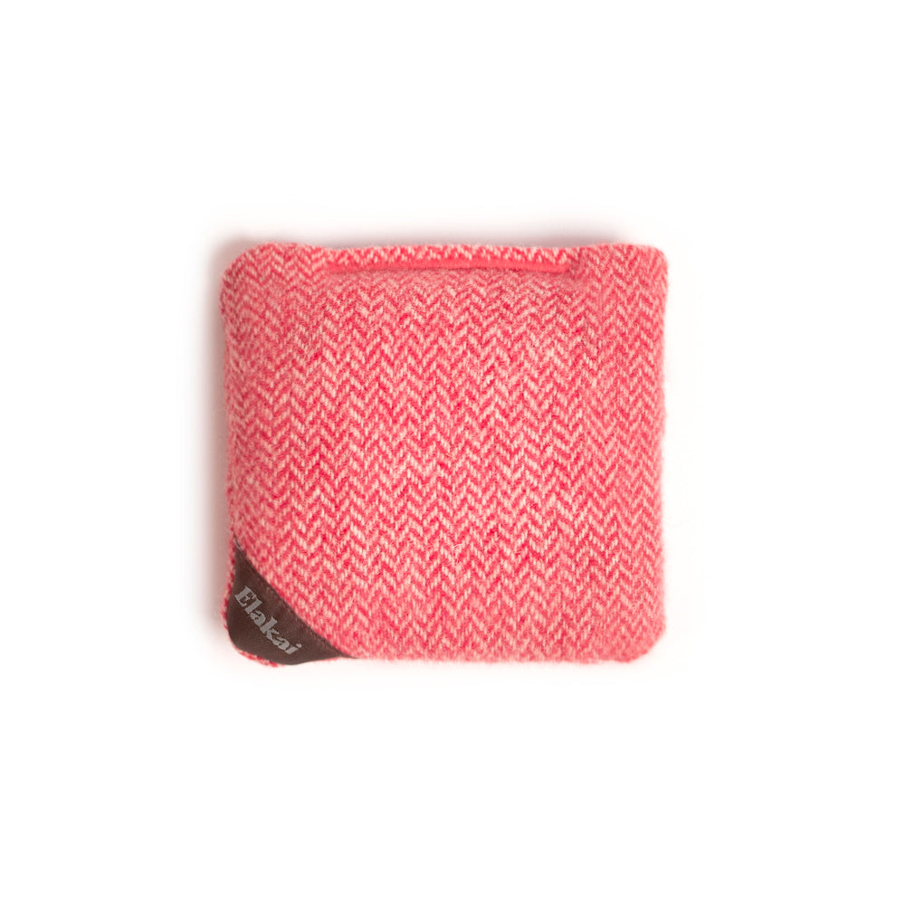 Pink woven pouch with a brand tag on a white background