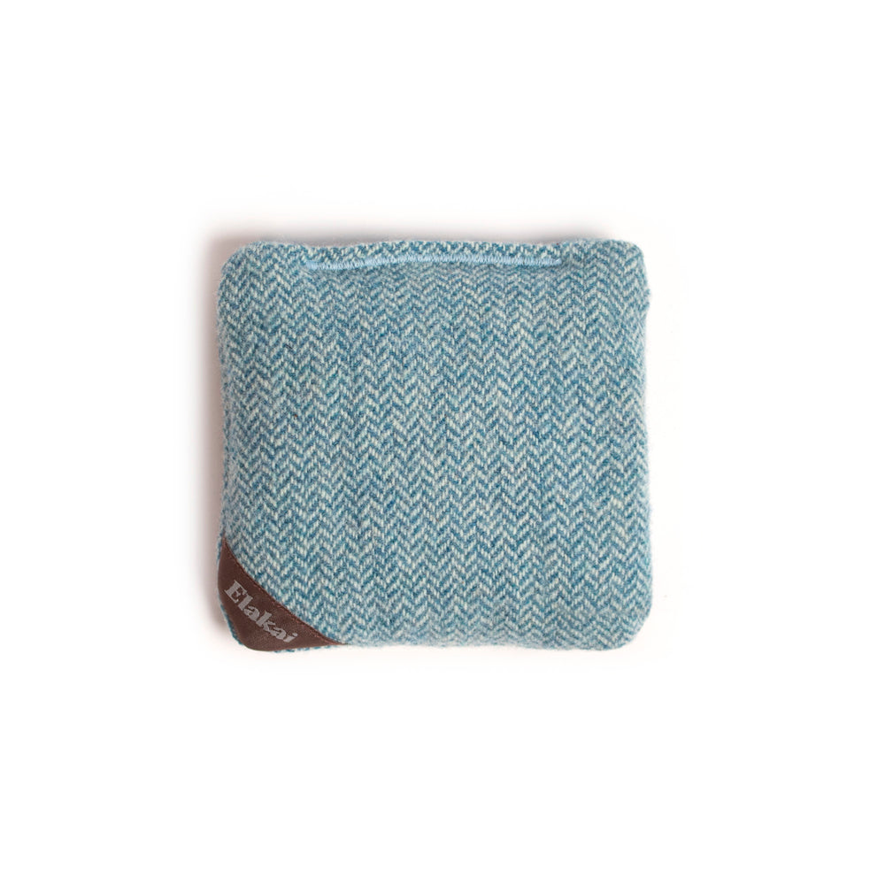 Teal and white herringbone patterned pouch with a brown label on a white background