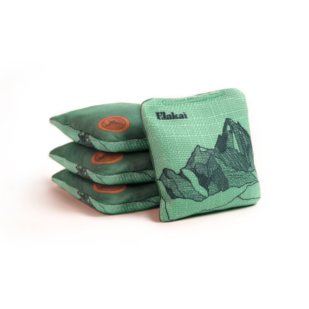 Green cornhole bags with mountain design and Flakai branding on a white background