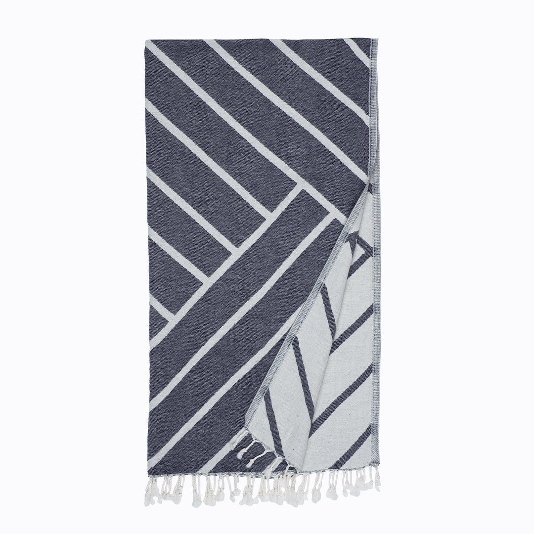 Navy and white patterned towel with fringes on a white background