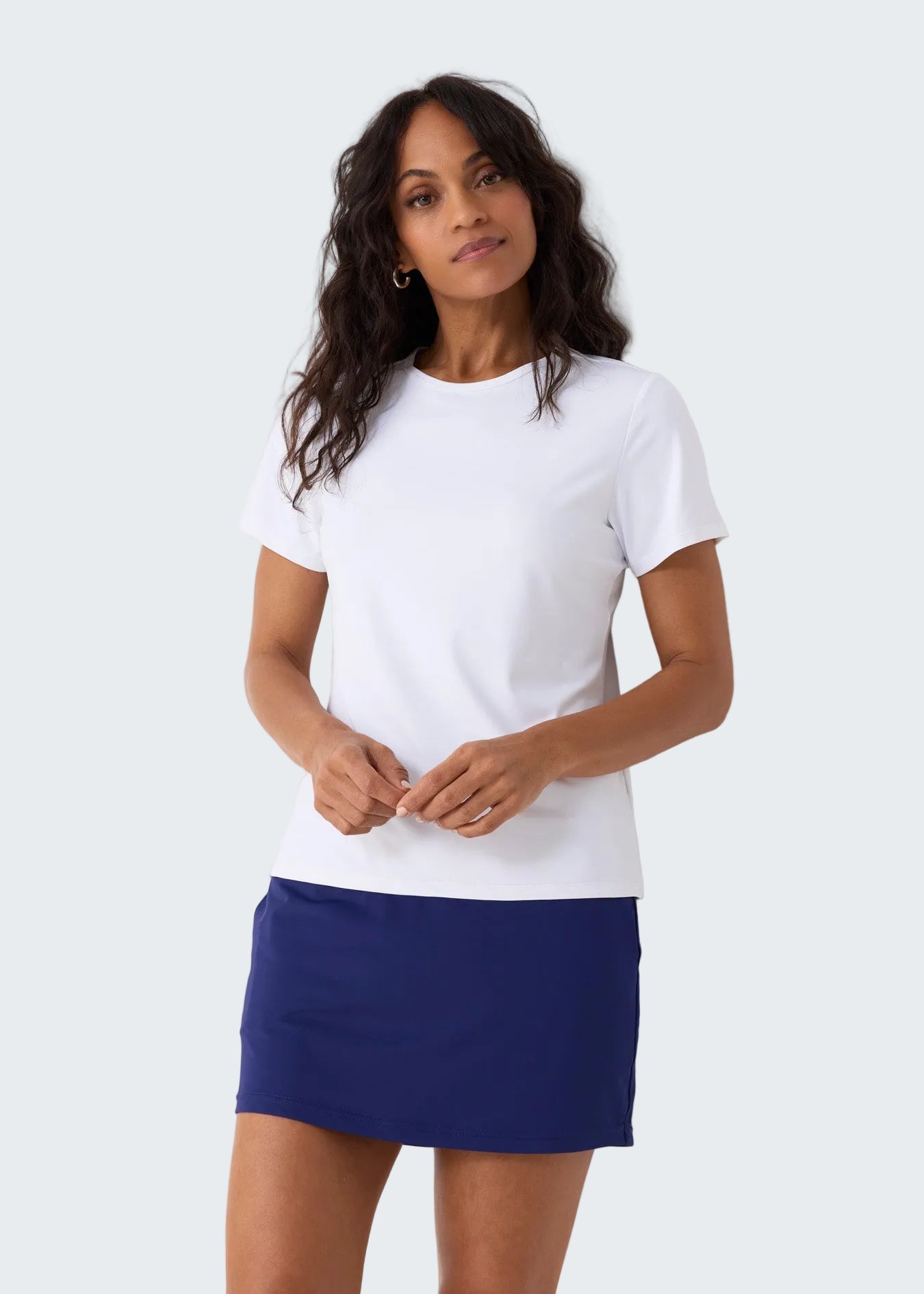 Woman wearing a white t-shirt and blue skirt against a white background