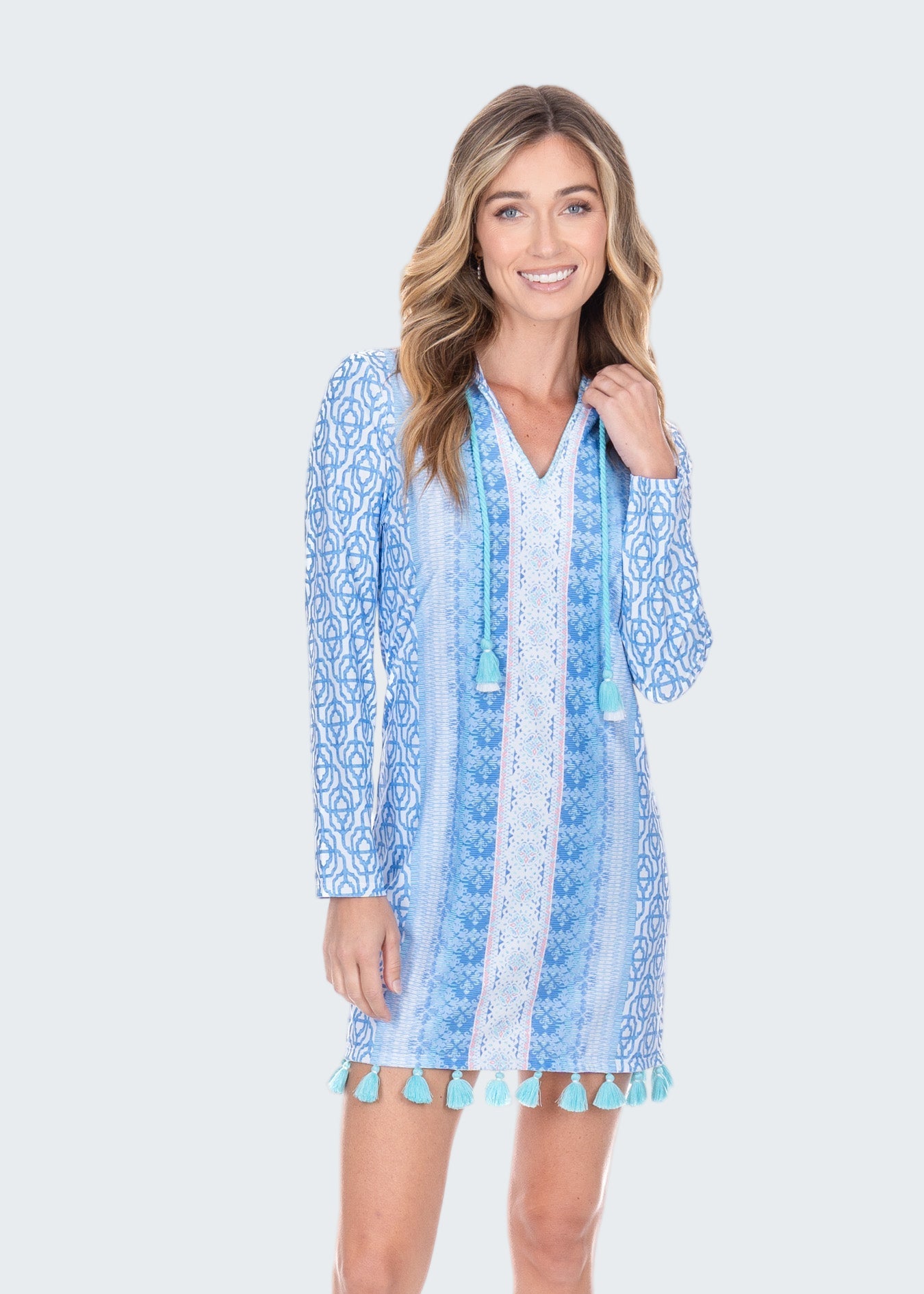 Woman wearing a blue patterned dress with pom-pom details on a white background