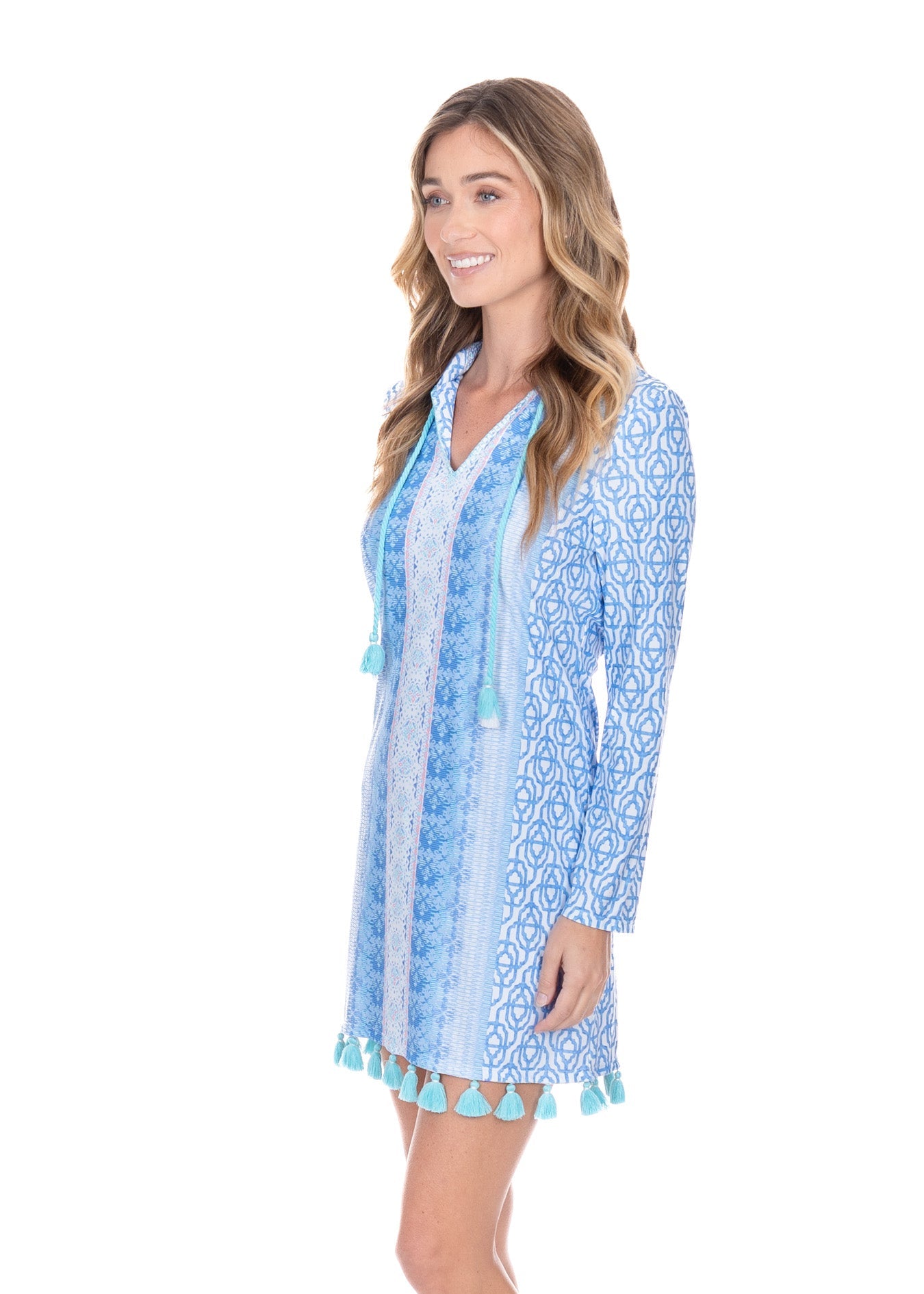 Woman wearing a blue patterned dress with tassel details on a white background