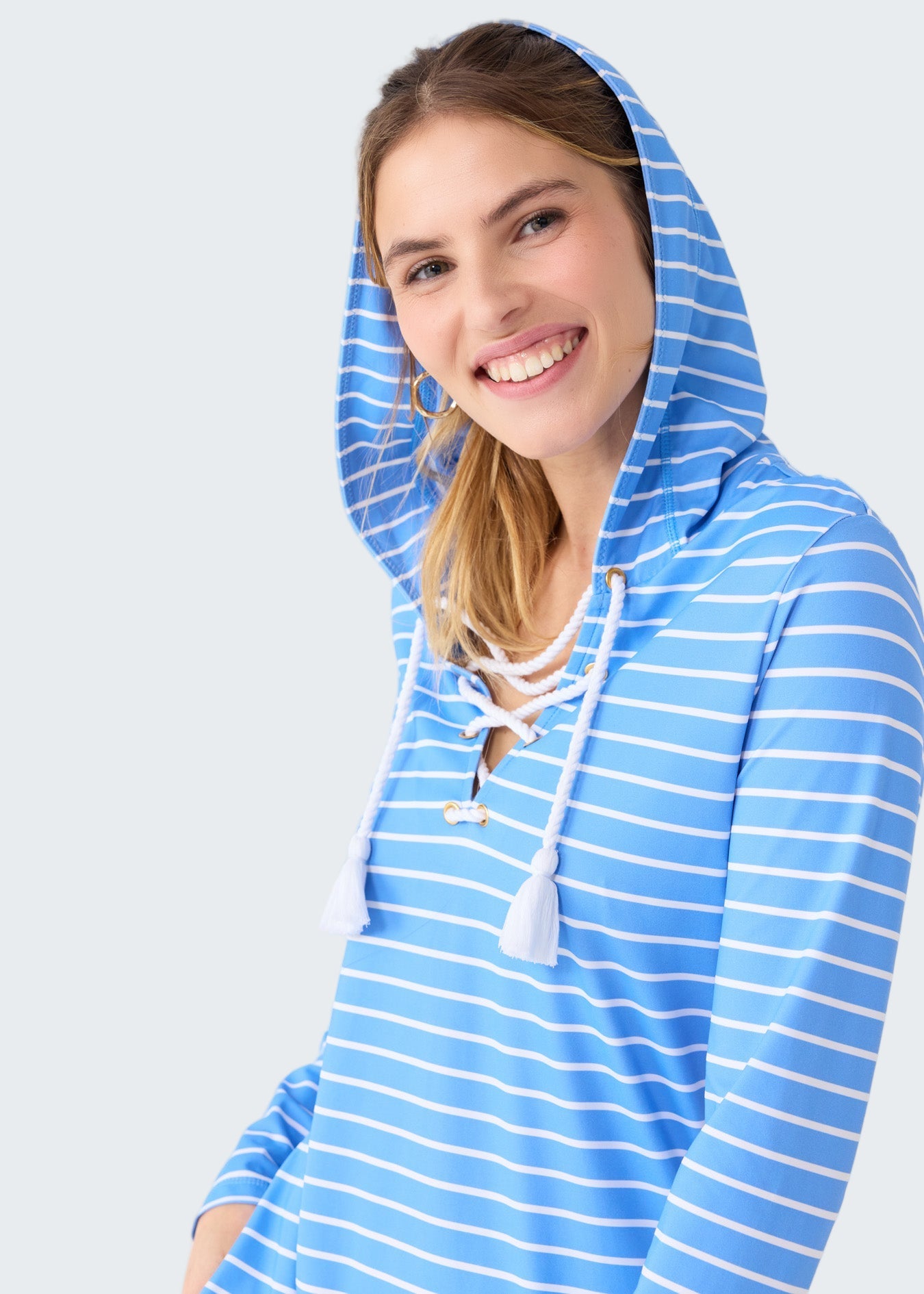 Woman wearing a blue and white striped hoodie on a plain background