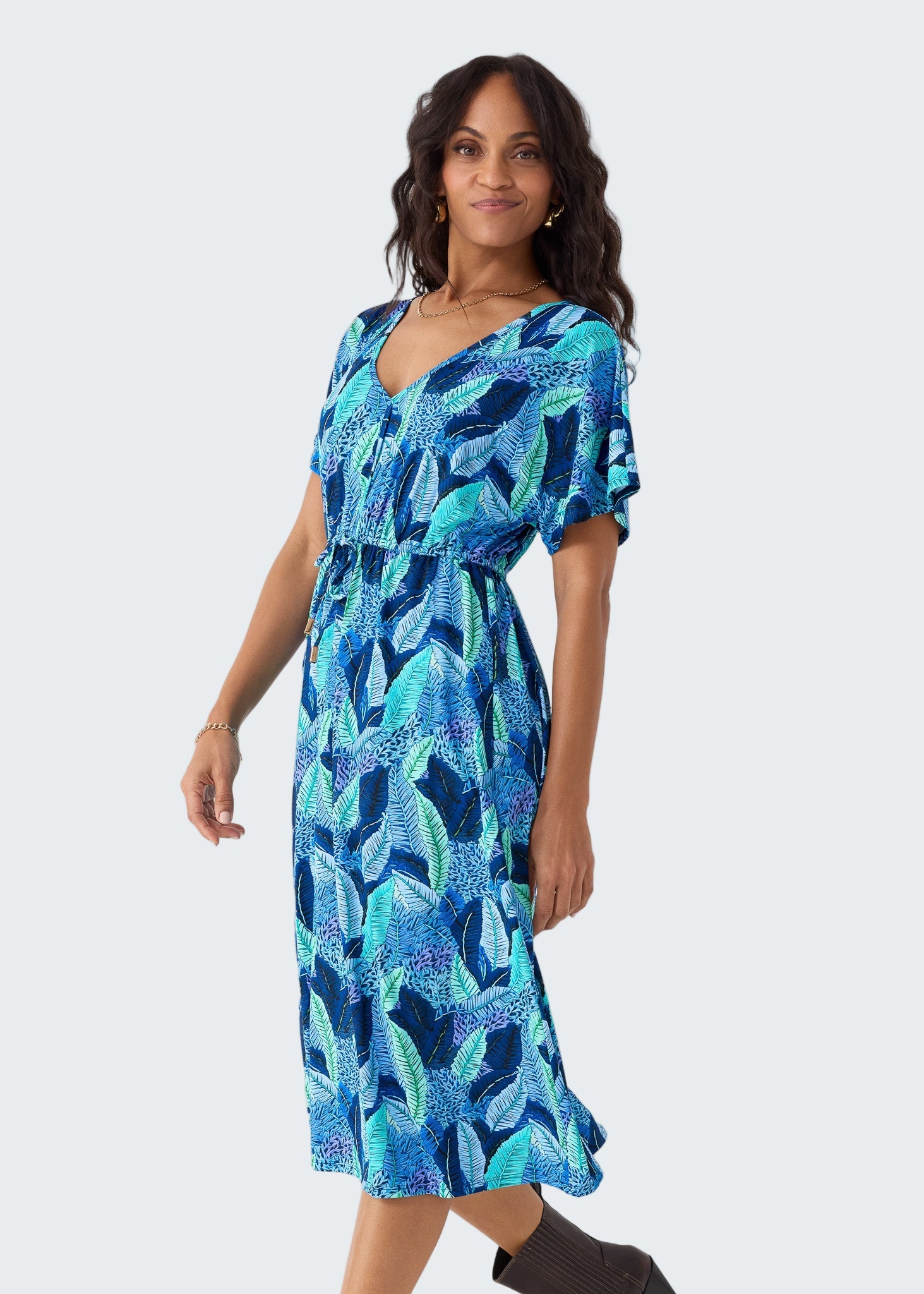 Woman wearing a blue and green patterned dress on a white background