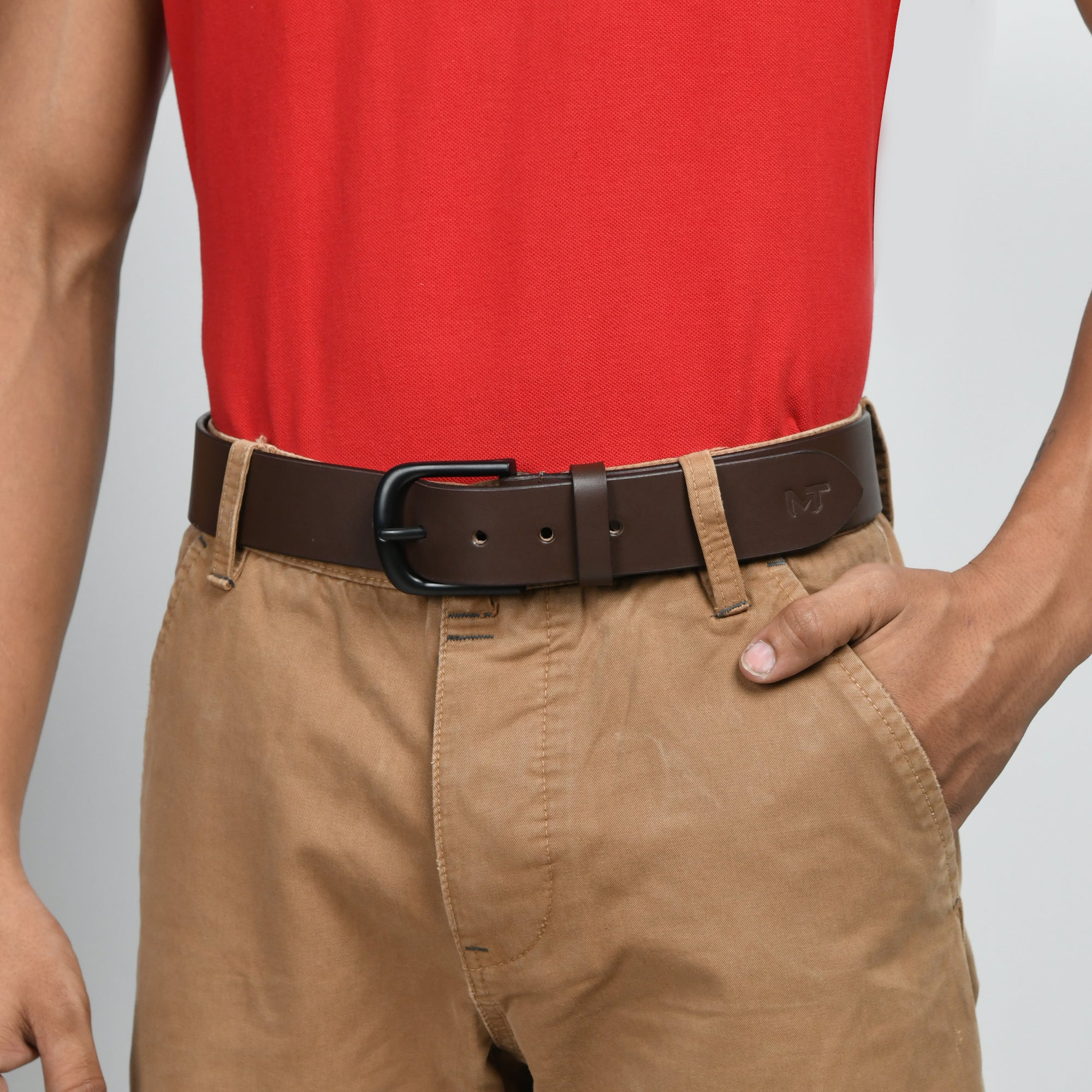 Person wearing a red shirt, brown belt, and beige pants on a gray background