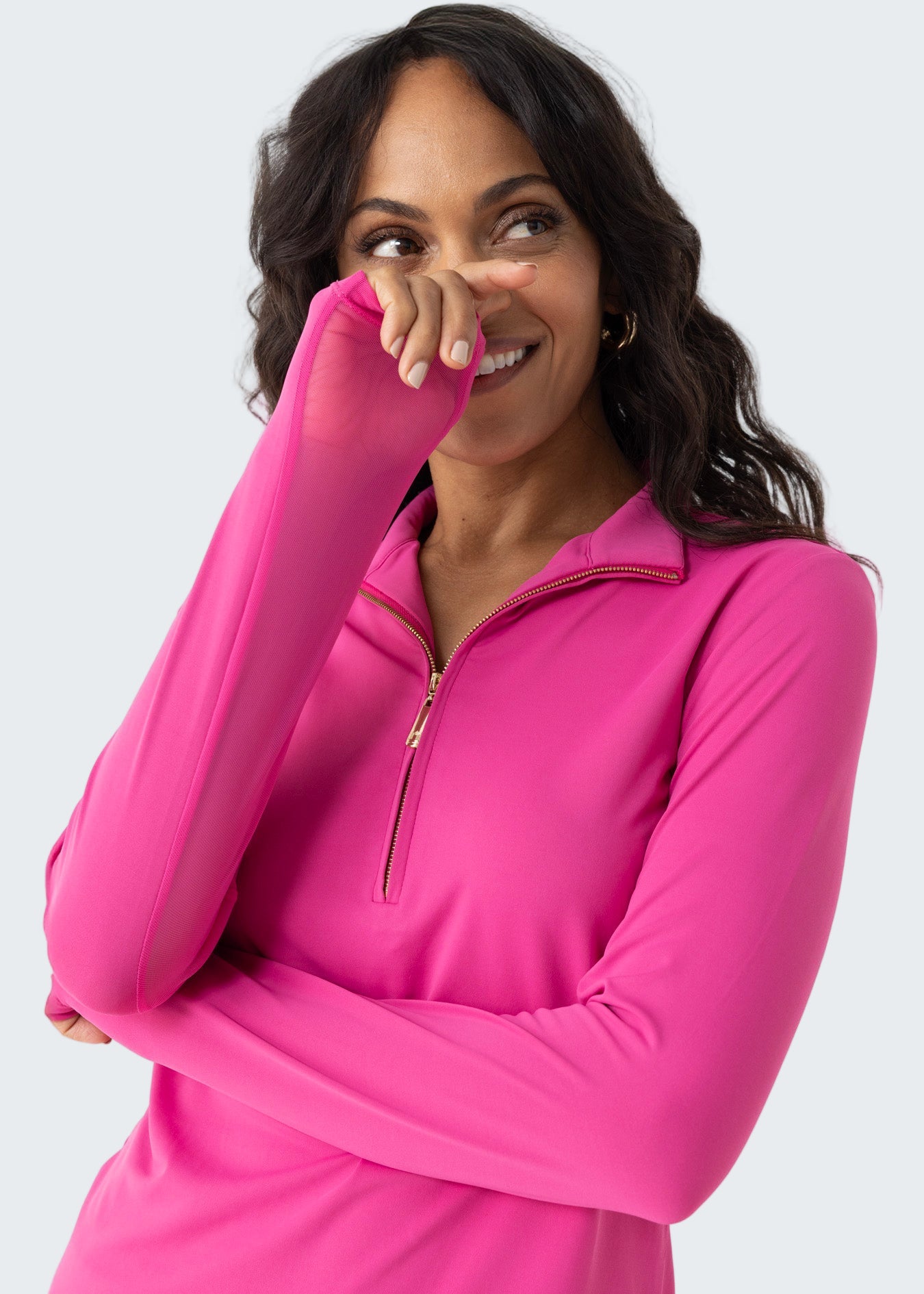 Woman wearing a bright pink long-sleeve top with a quarter zip on a white background