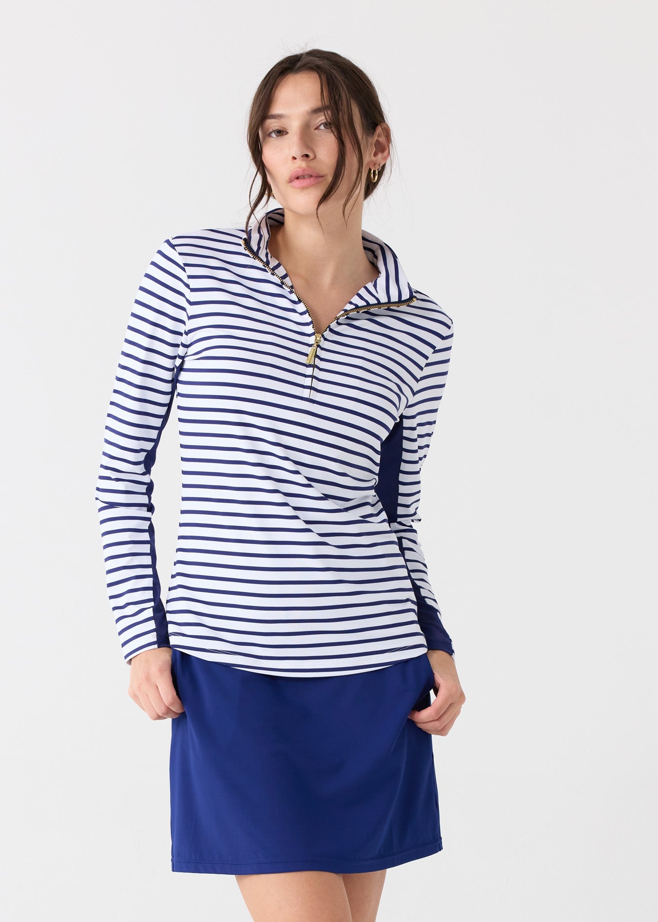 Woman wearing a striped long-sleeve top and blue skirt on a white background