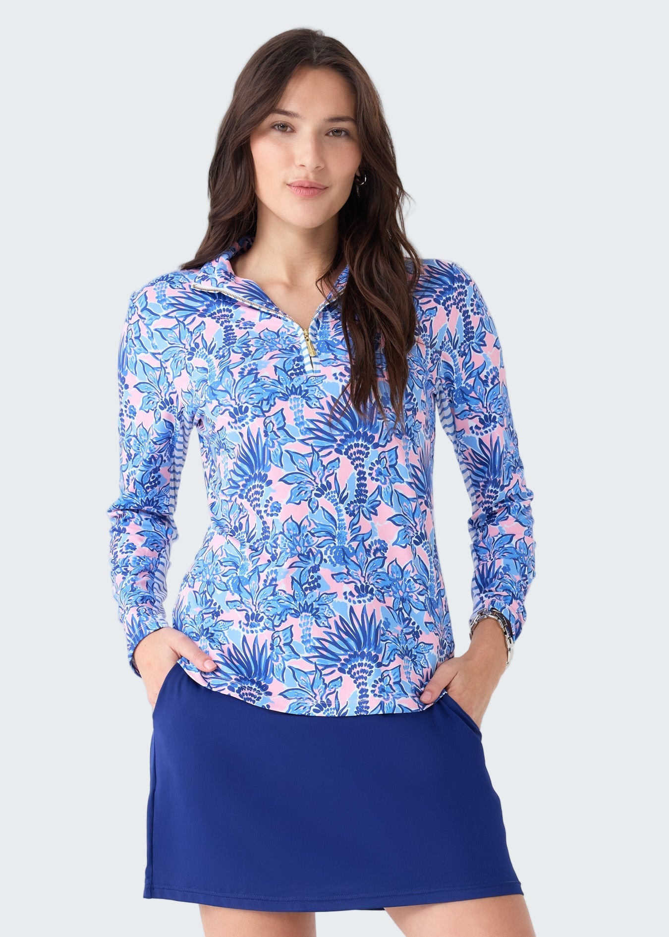 Woman wearing a blue and pink floral long-sleeve top and blue skirt on a white background