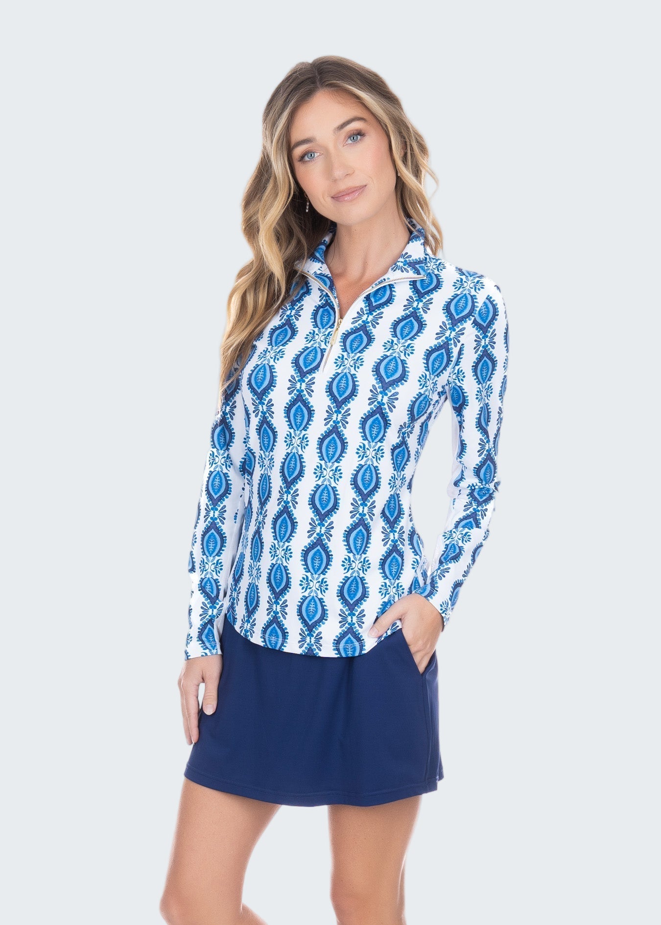 Woman wearing a blue and white patterned shirt with a navy skirt on a white background