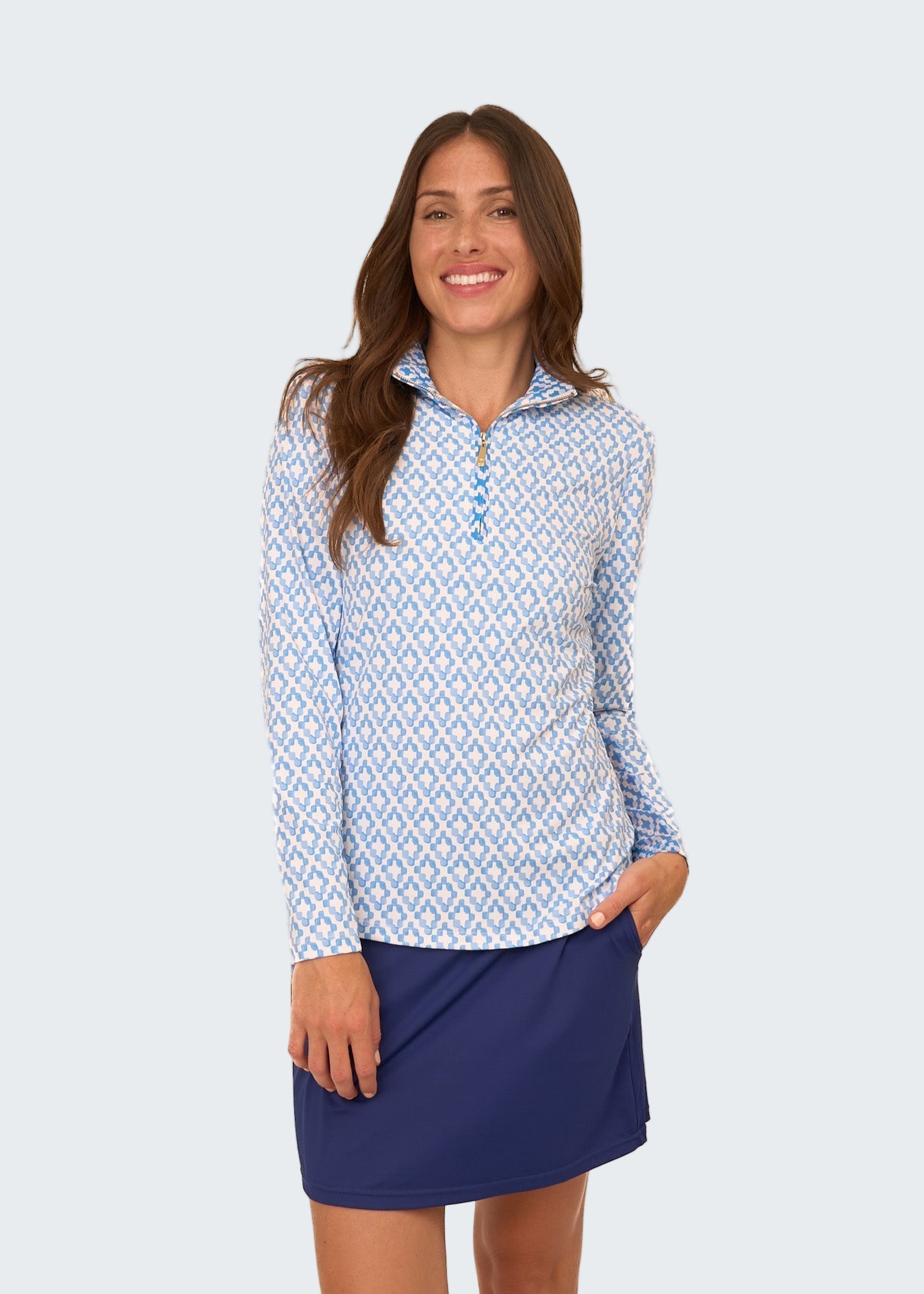 Woman wearing a blue and white patterned long-sleeve shirt with a navy skirt on a white background