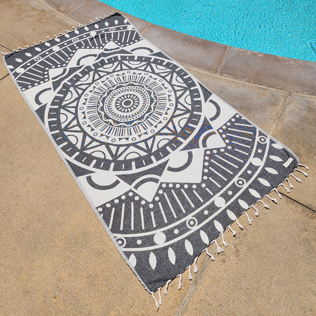 Decorative rug with geometric pattern on a stone surface near a pool.