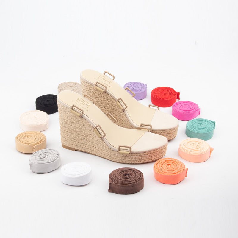 Beige wedge sandals with colorful shoelaces on a white background