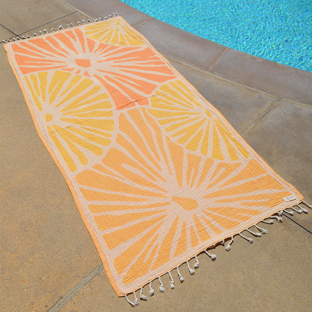 Decorative outdoor rug with sunburst pattern on a stone patio near a pool.