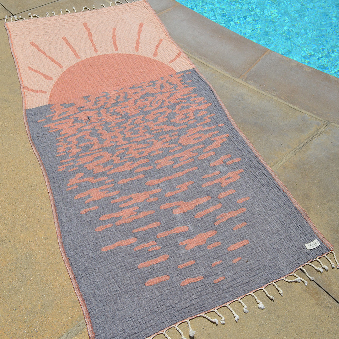 Decorative towel with sunset design on a poolside floor