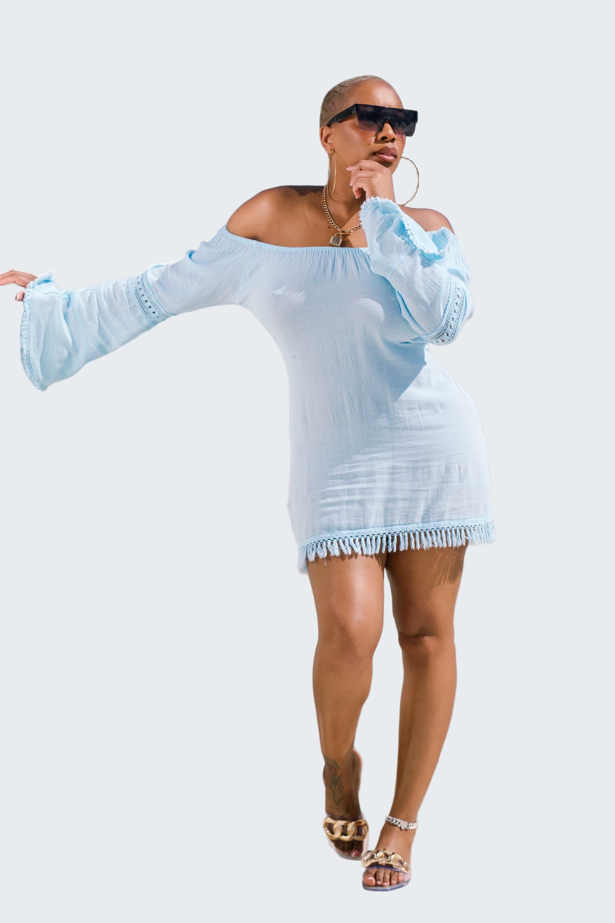 Woman in a light blue dress standing on a rooftop with a cityscape background