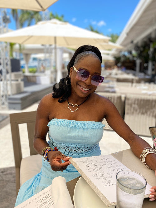 Woman in a blue strapless dress sitting outdoors with a drink and menu.