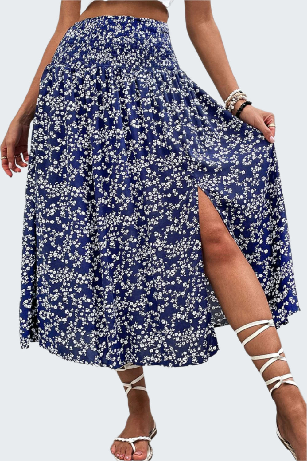 A high-waisted, floral print midi skirt with a slit, paired with white strappy sandals.