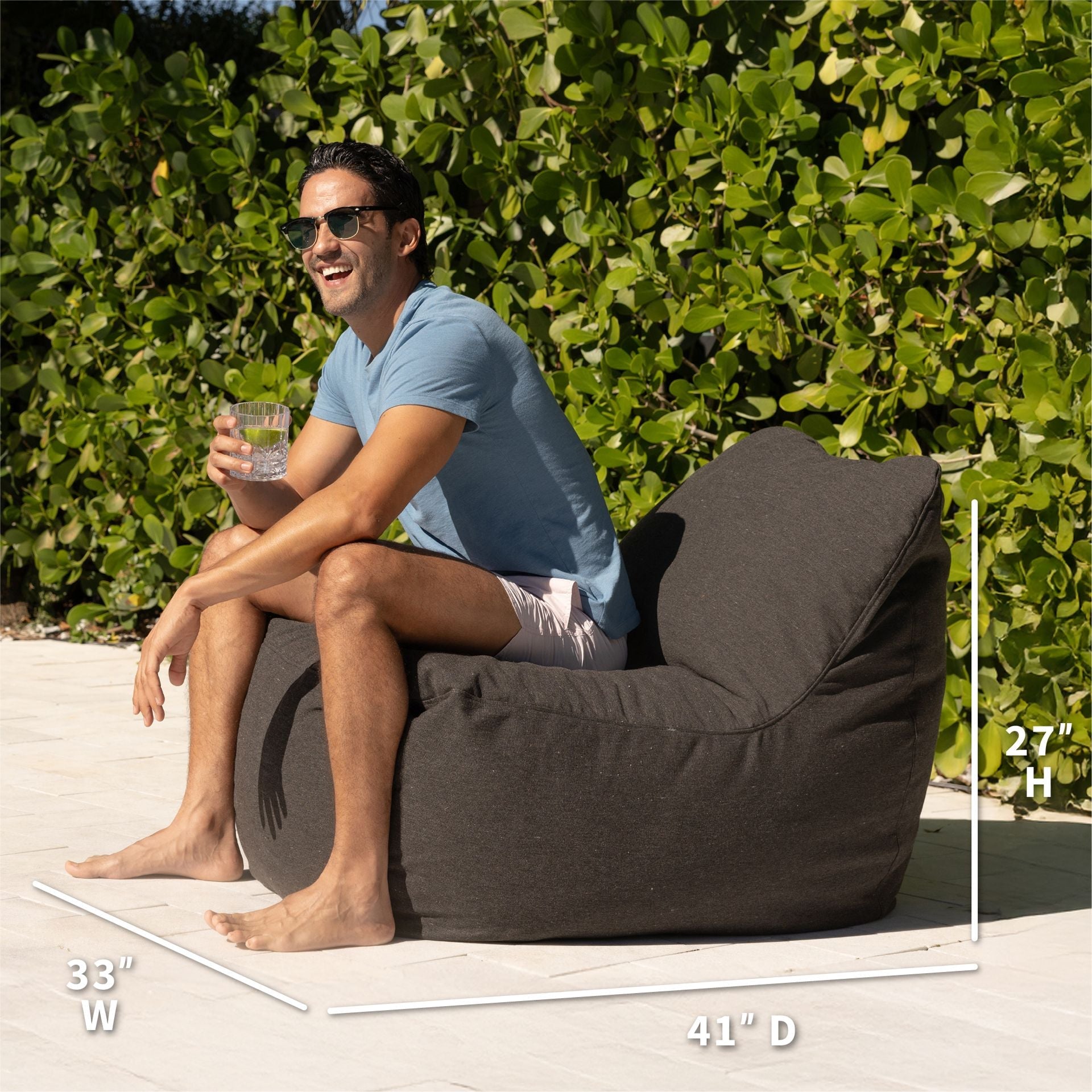 Man sitting on a bean bag chair outdoors with dimensions displayed