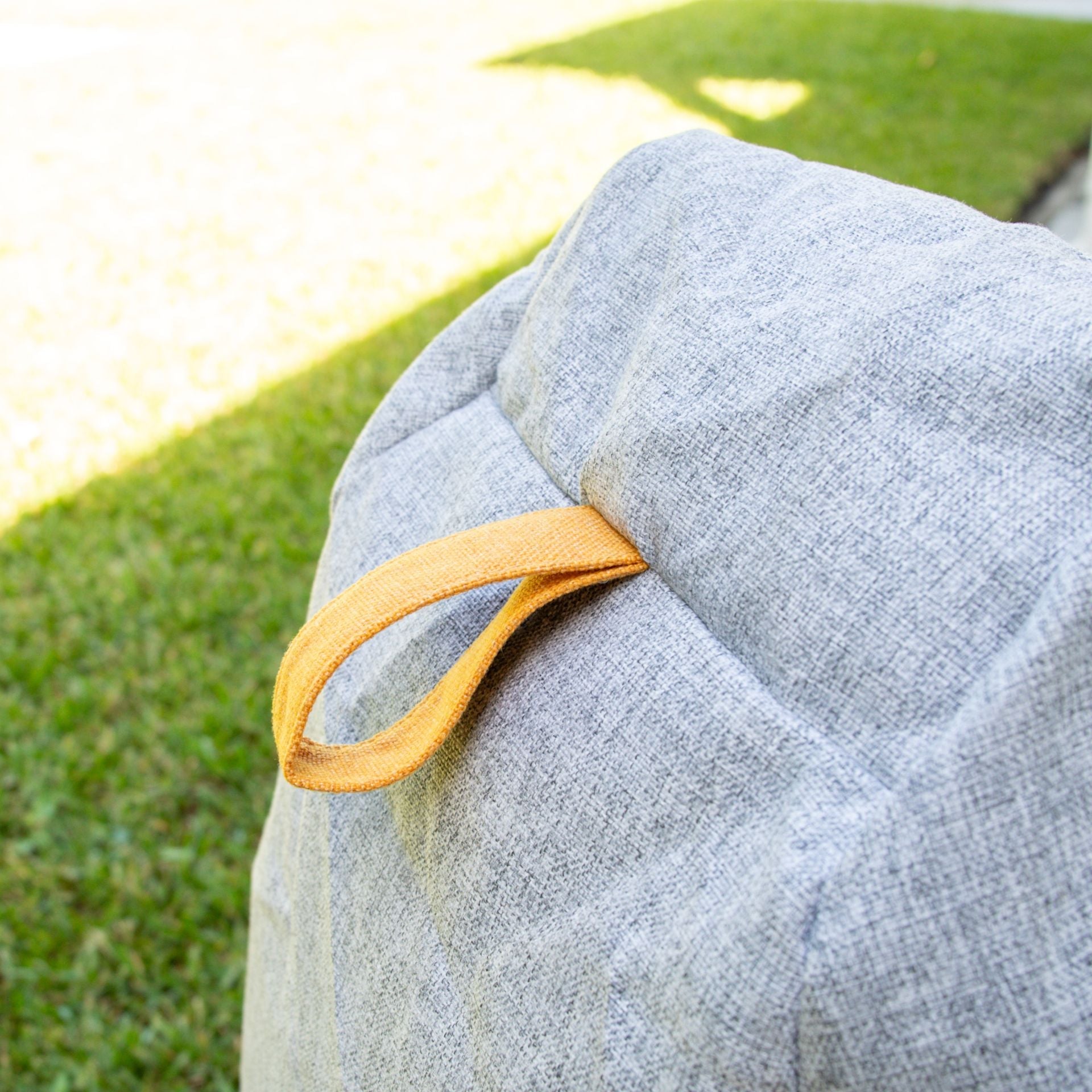 Gray bag with a yellow strap on grass