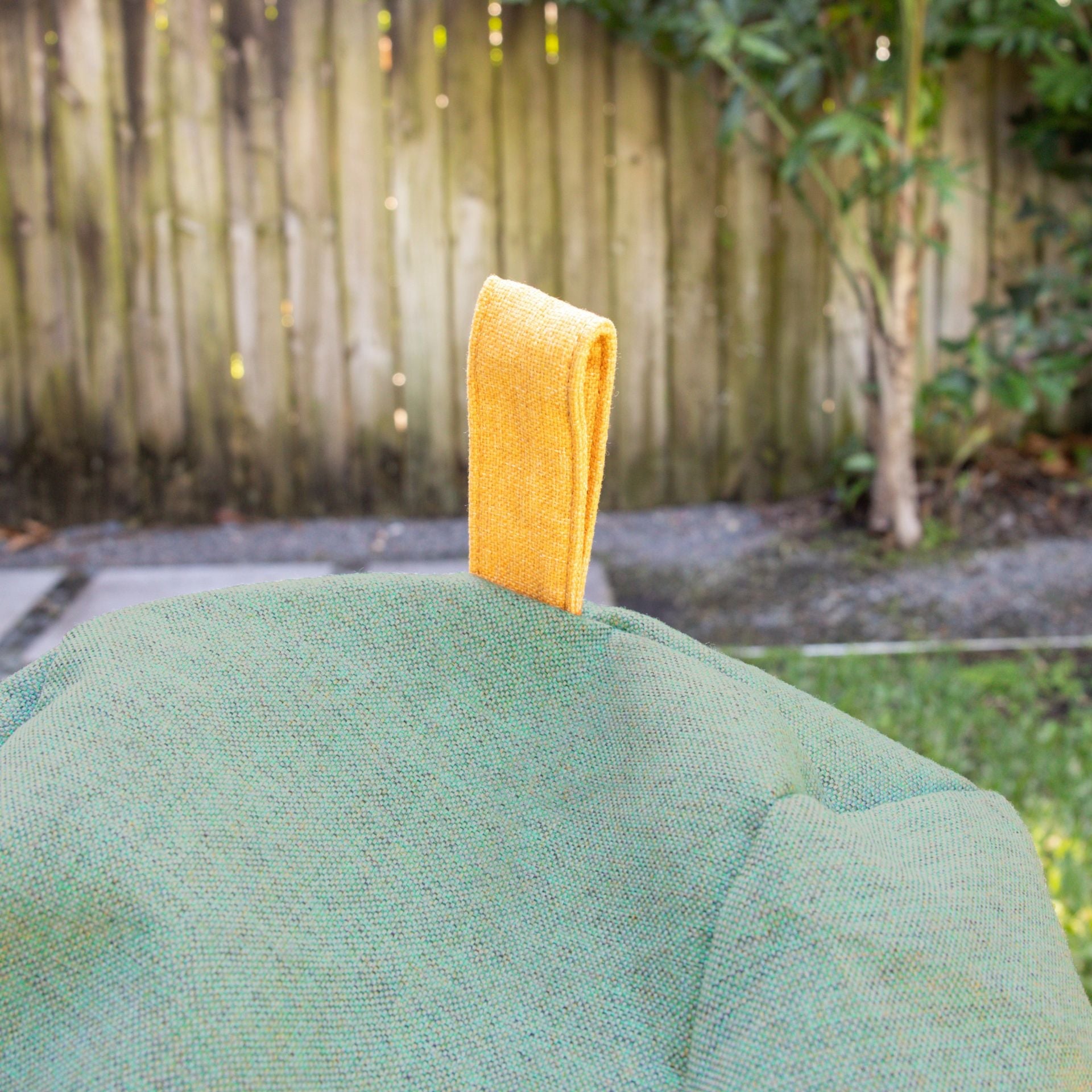 Green fabric with a yellow handle against a blurred outdoor background