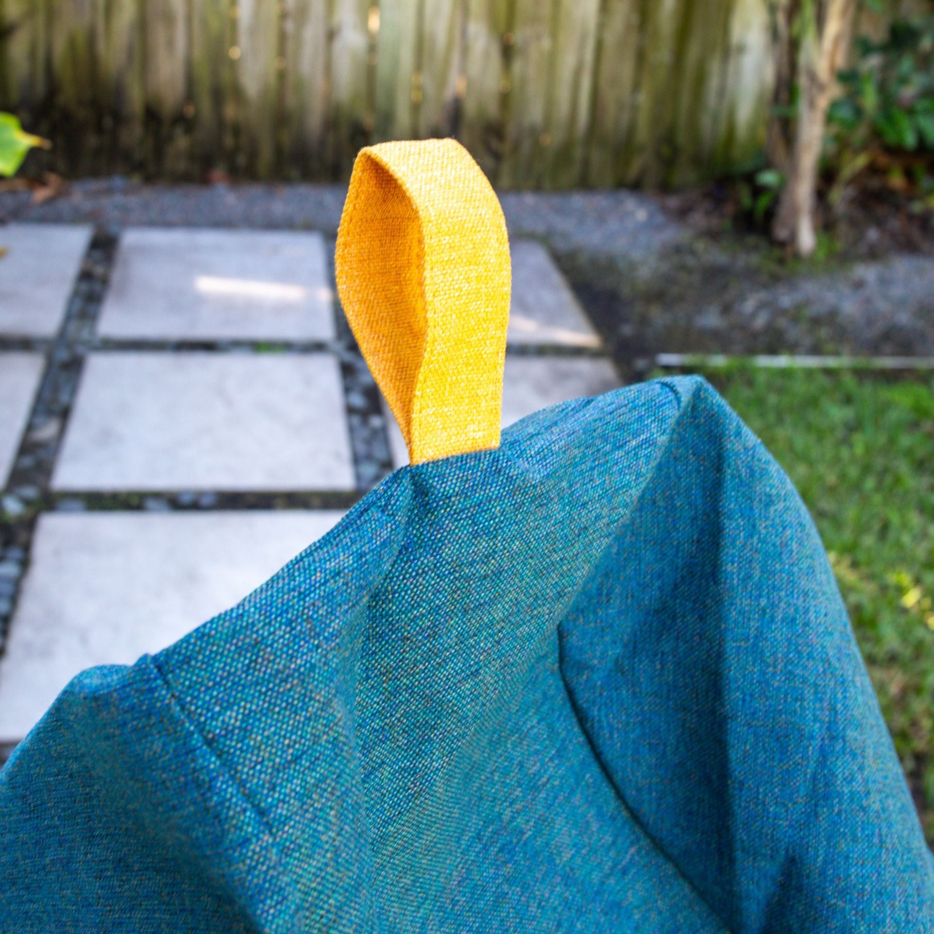 Blue fabric with a yellow tag on a blurred outdoor background