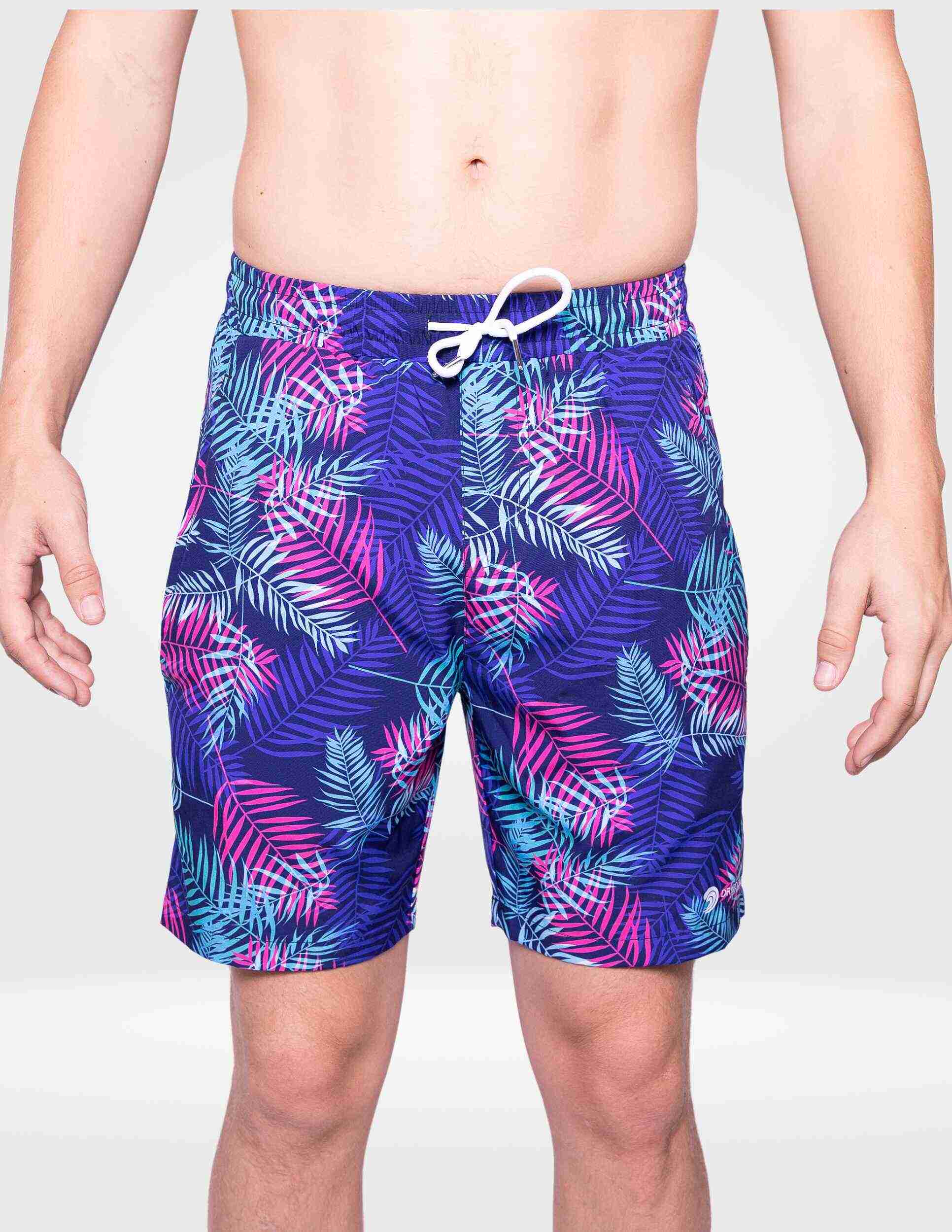 Person wearing colorful tropical leaf patterned shorts on a plain background