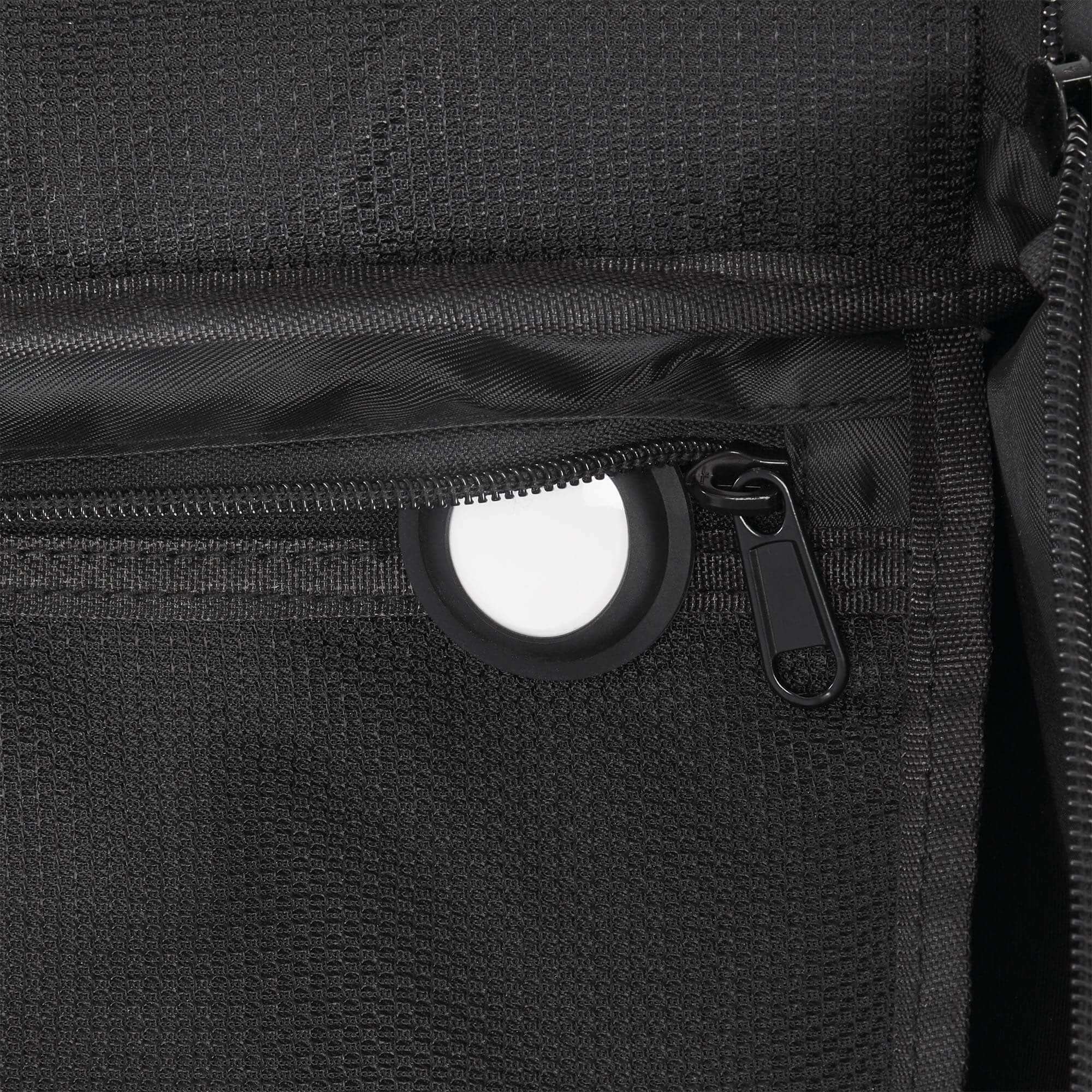 Close-up of a black backpack zipper with a white circle on a dark background