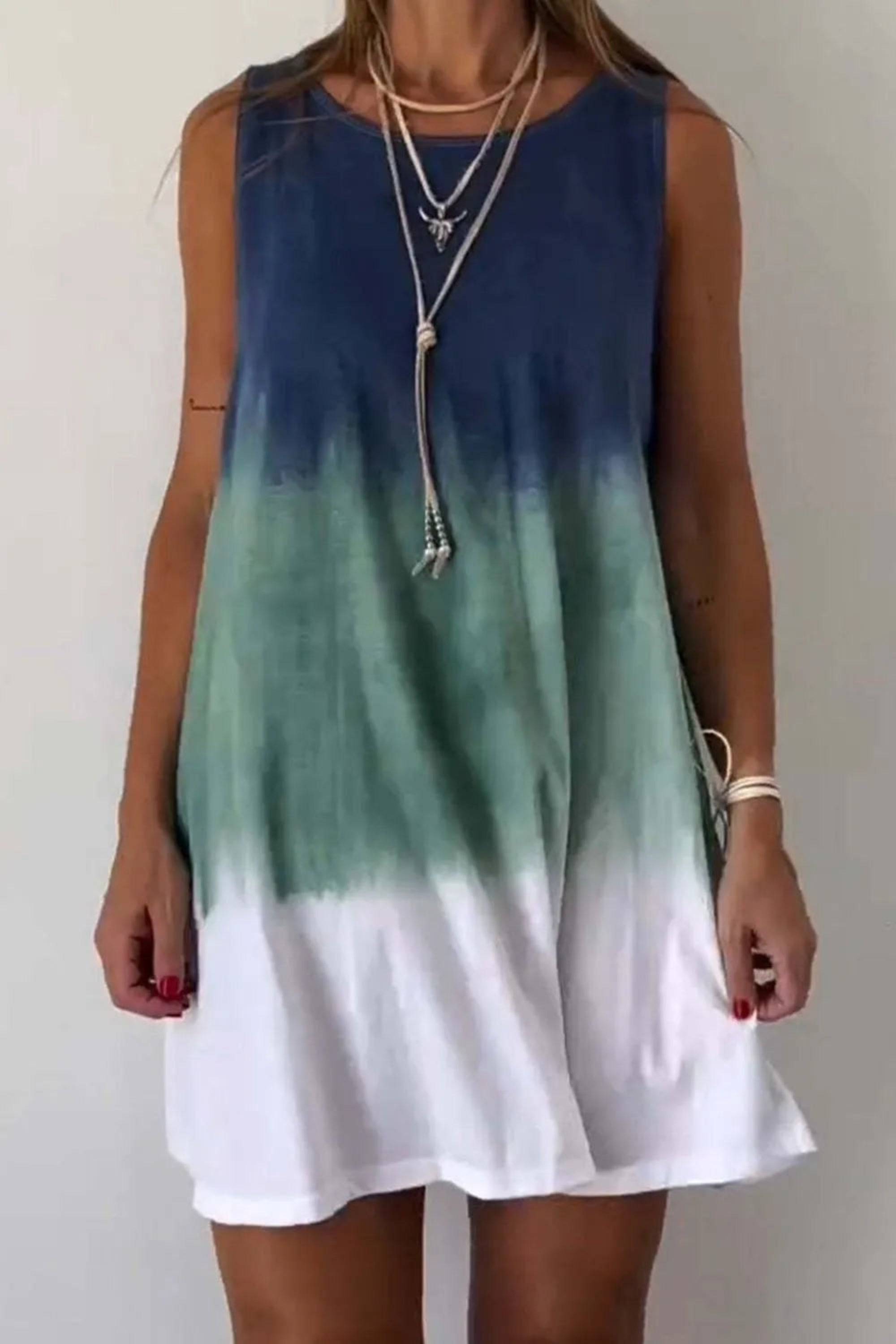 A sleeveless mini tank dress with tie-dye patterns in blue and green shades on a white background.