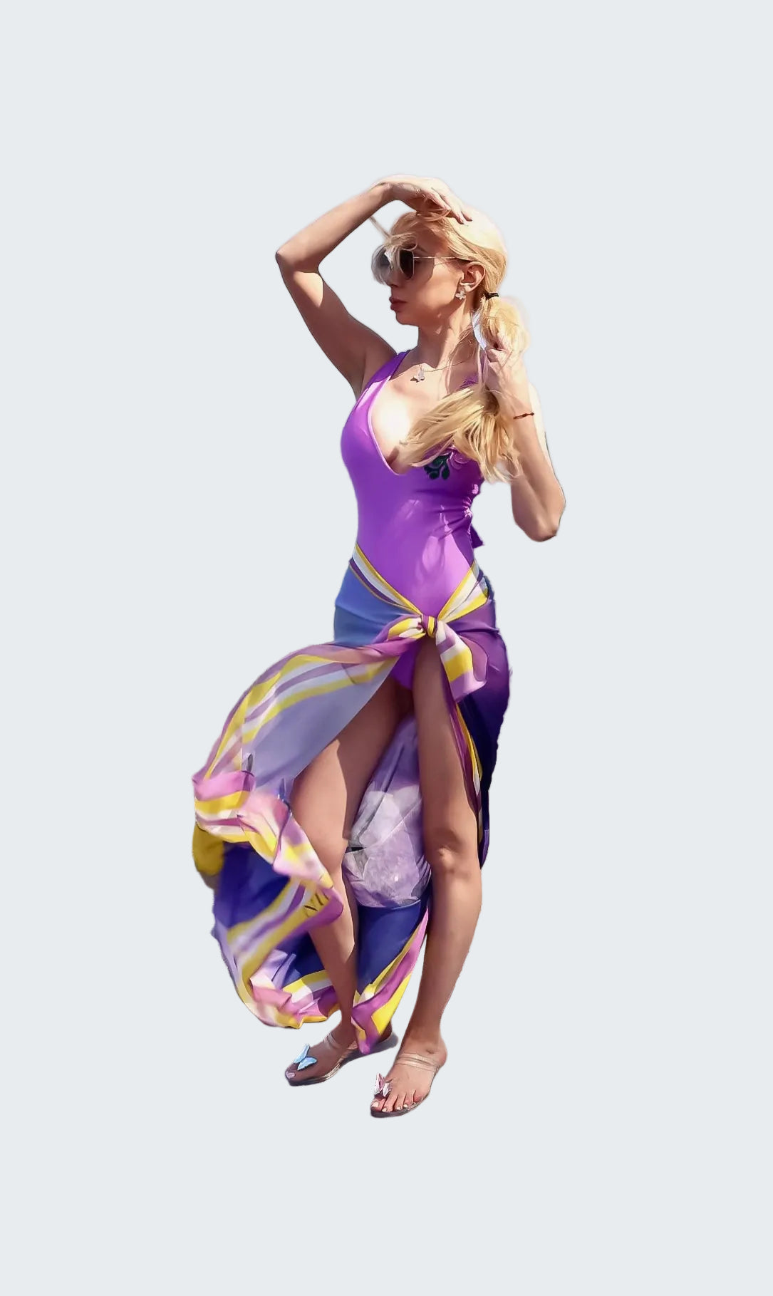 Woman in a colorful dress standing on rocks by the ocean