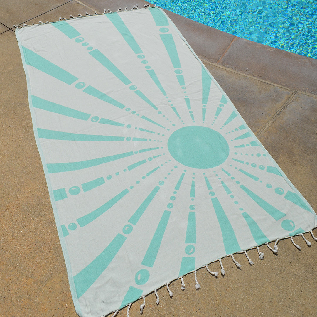 Beach towel with sunburst pattern on a poolside floor