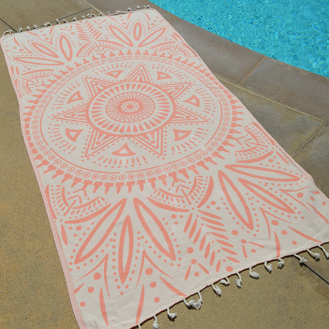 Patterned towel with tassels on a poolside floor