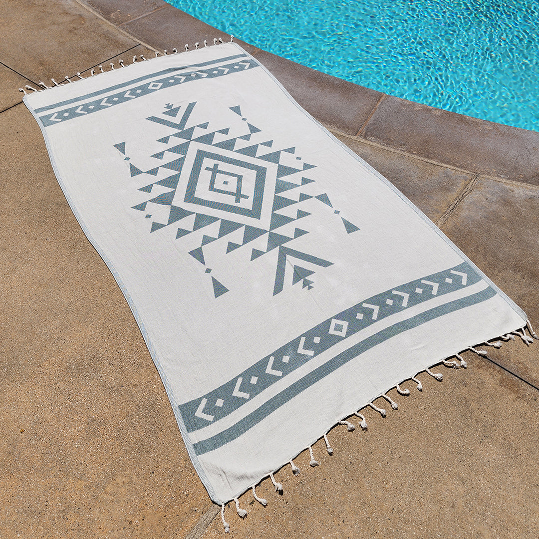 Geometric patterned towel on a stone surface near a pool