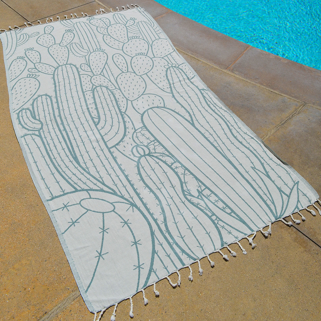 Towel with cactus pattern on a stone surface near a pool